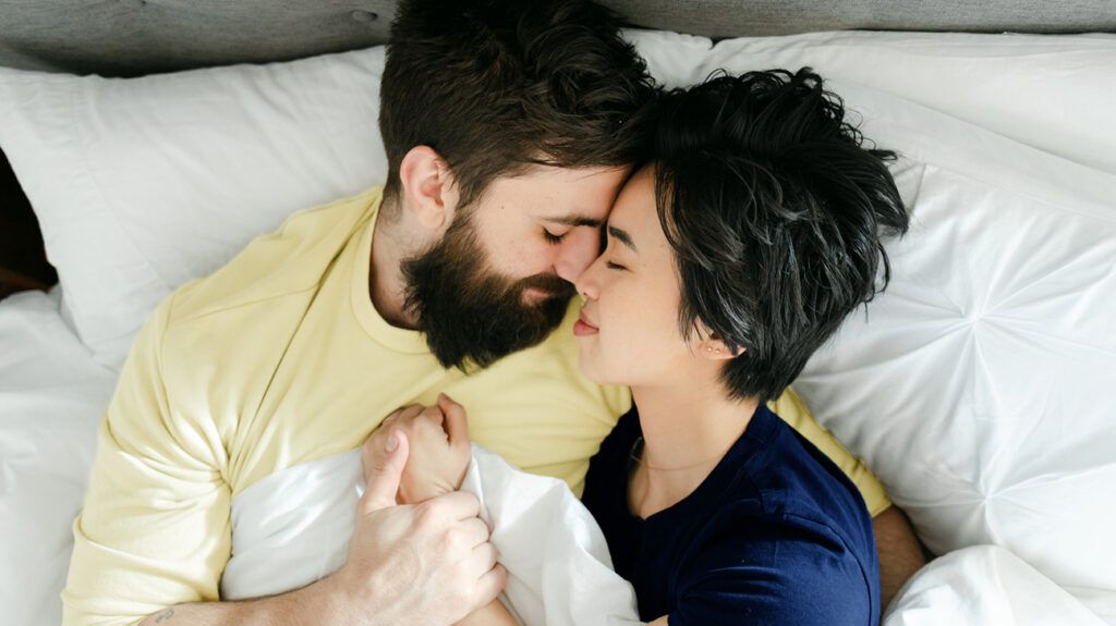 Happy couple cuddling in bed