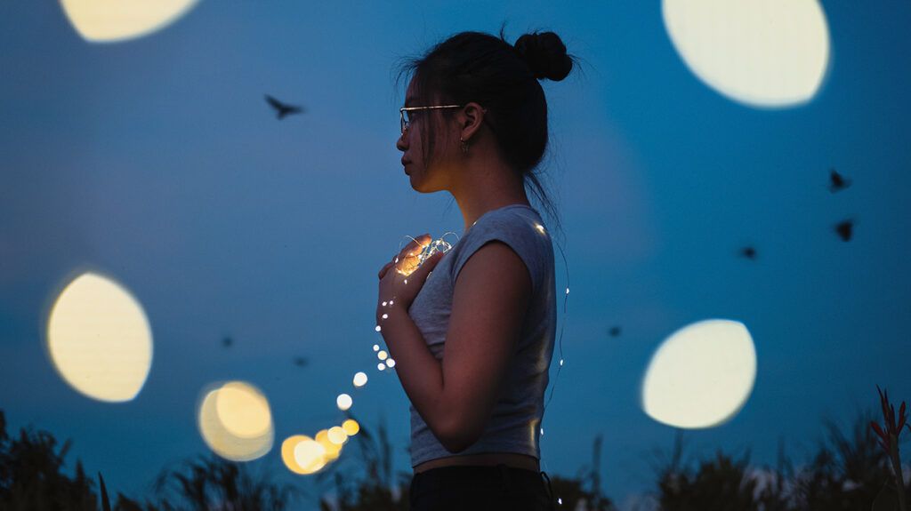 Abstract image of woman holding string lights at night